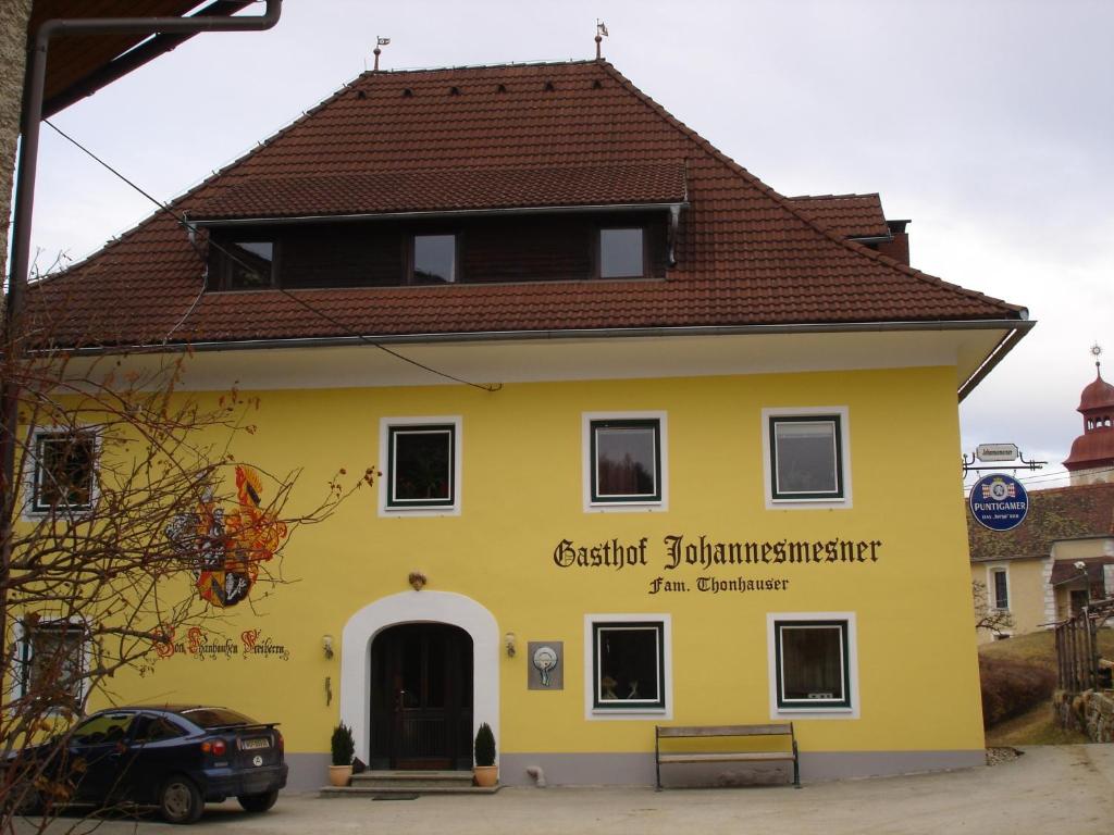 ein gelbes Gebäude mit braunem Dach in der Unterkunft Gasthof Johannesmesner in Sankt Paul im Lavanttal