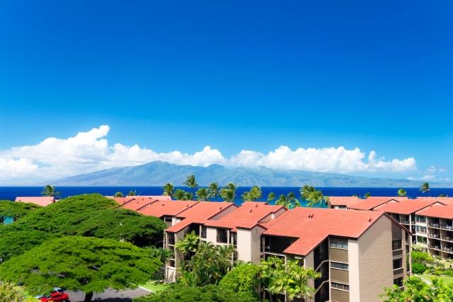 un grupo de edificios de apartamentos con árboles y el océano en Kaanapali Shores Studio #742 en Lahaina