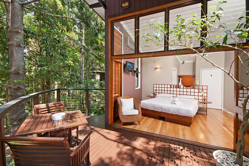 a room with a bed and a table on a balcony at Azabu Retreat & Spa in Byron Bay