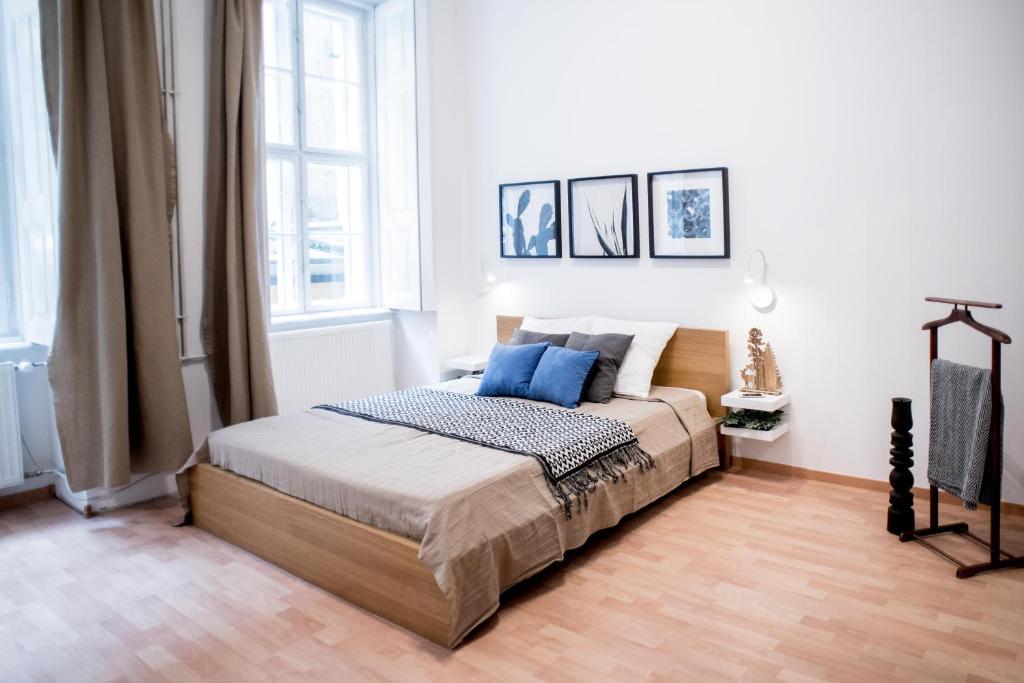 a white bedroom with a bed with blue pillows at City Heart Apartment in Budapest