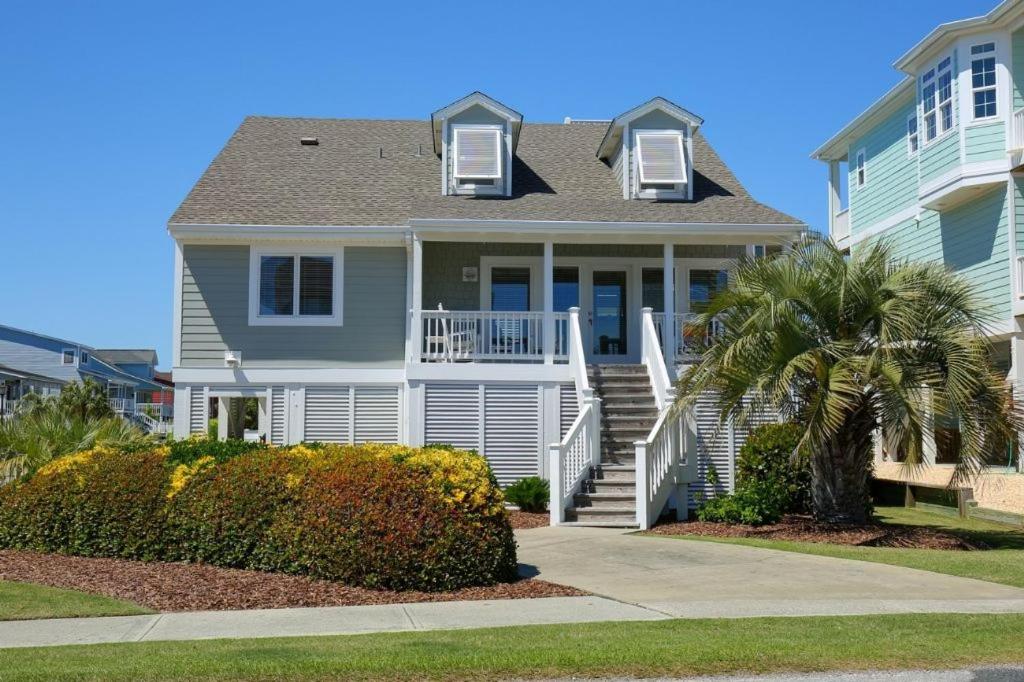 a white house with a palm tree in front of it at Holden Jeanie in Holden Beach