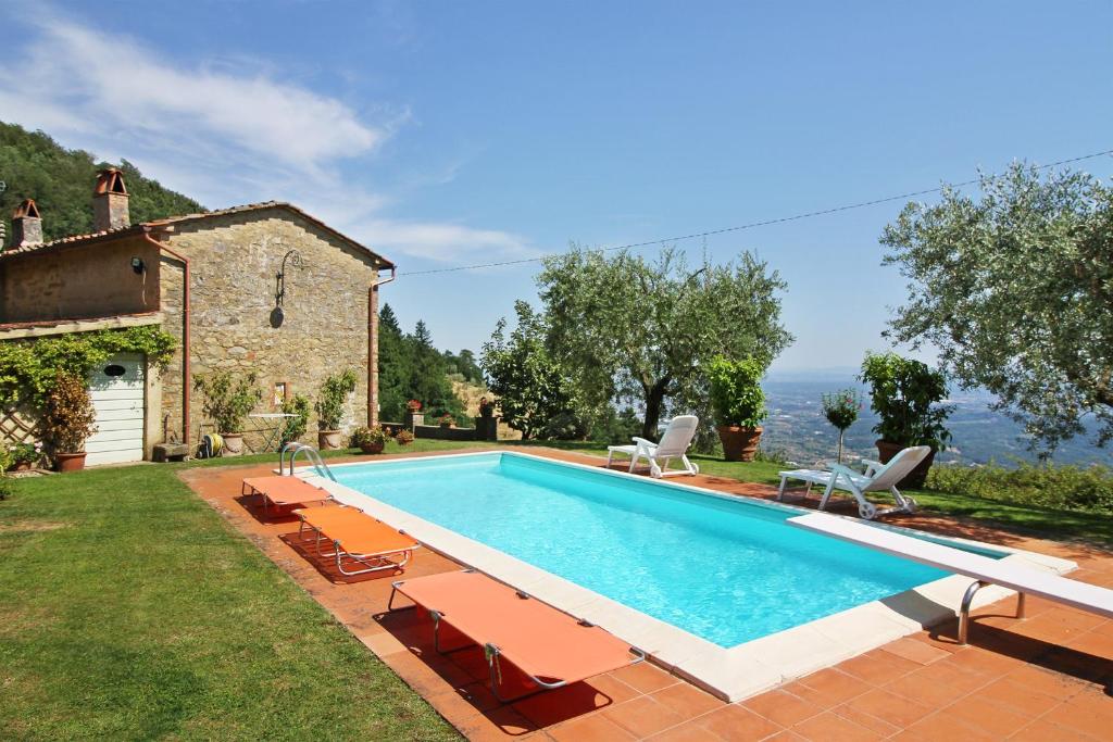 an outdoor swimming pool with chairs and a house at Villa Petrognano in Petrognano