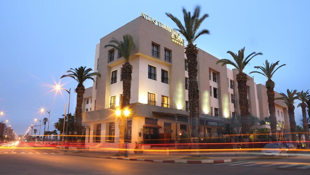 a building with palm trees in front of a street at Terminus City Center Oujda in Oujda