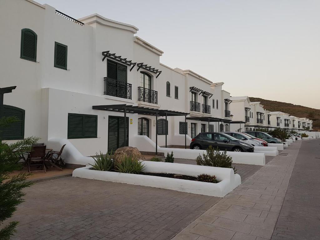 a row of white houses with cars parked on a street at Casa Maria en Agaete in Agaete