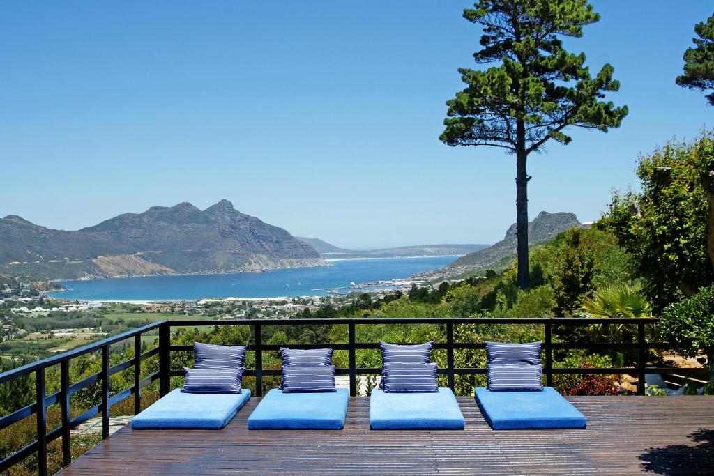 a group of blue chairs on a deck with a view of the water at Dreamhouse Guest House in Hout Bay