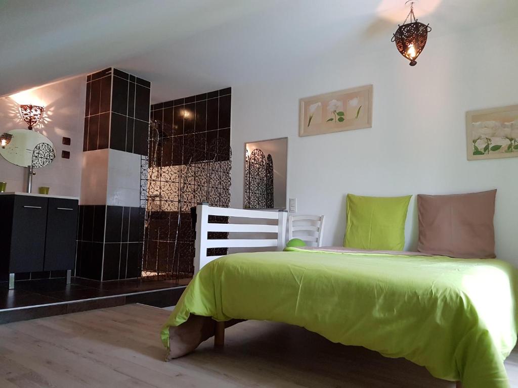 ein Schlafzimmer mit einem grünen Bett in einem Zimmer in der Unterkunft Le vieux Pressoir in Saint-Germain-lès-Arlay