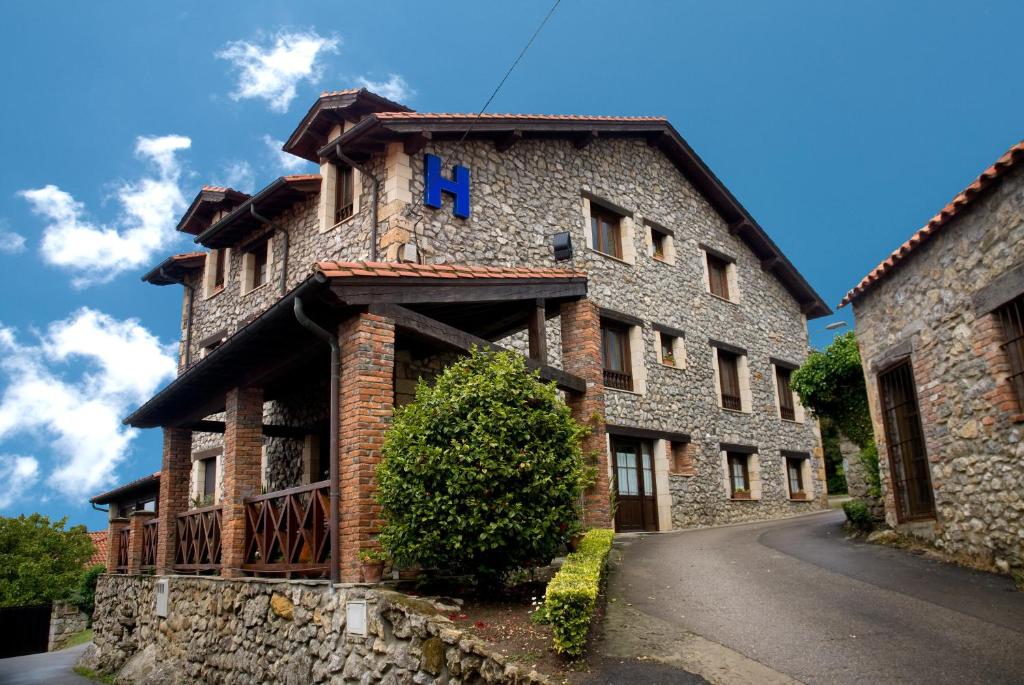 un edificio in pietra con un cartello blu sopra di Posada Rural Entrecomillas a Comillas