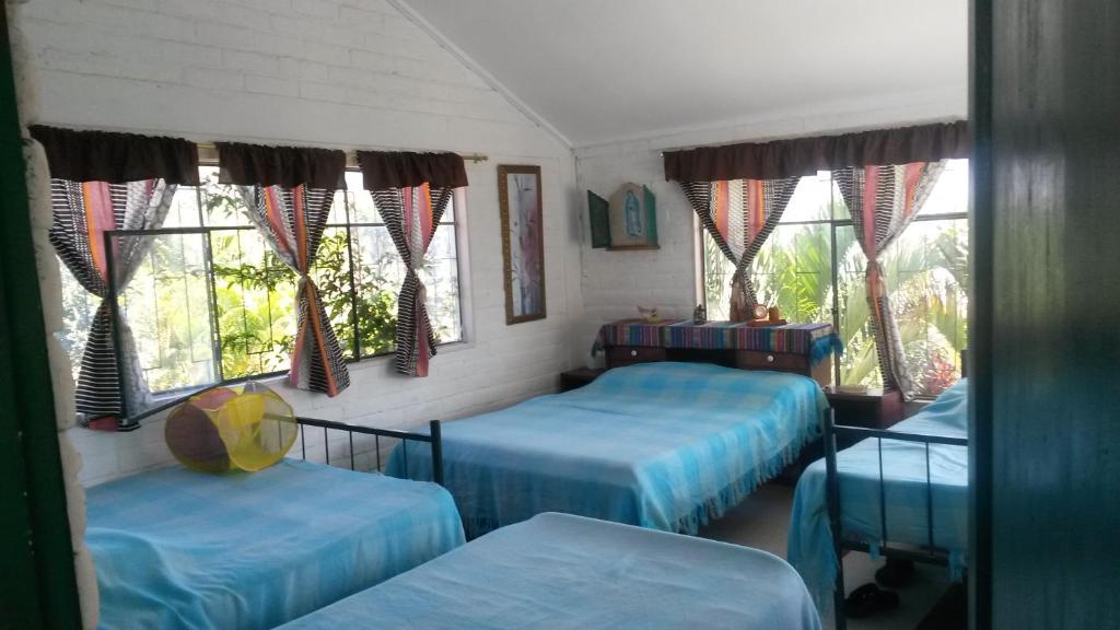 a room with two beds and two windows at NUESTRA CASA -OUR HOME Yunguilla Valley by A2CC in Tobachirin