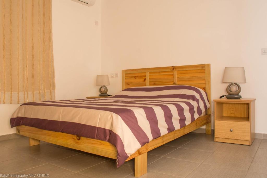 1 dormitorio con 1 cama de madera y 2 mesitas de noche en Villa Alexis - Location de vacances à Trou aux Biches, en Trou aux Biches