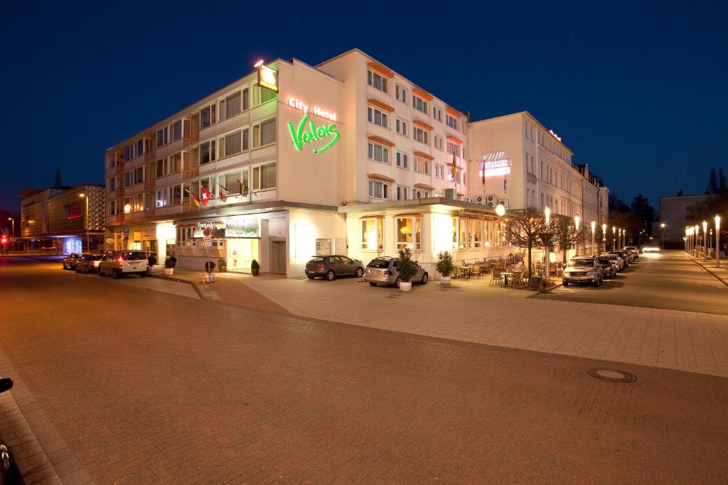 un edificio en una calle con coches estacionados en un estacionamiento en City Hotel Valois, en Wilhelmshaven