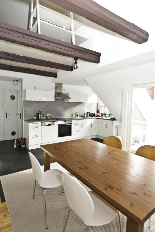 a kitchen with a wooden table and white chairs at Altstadt-Domizil 6 in Leer