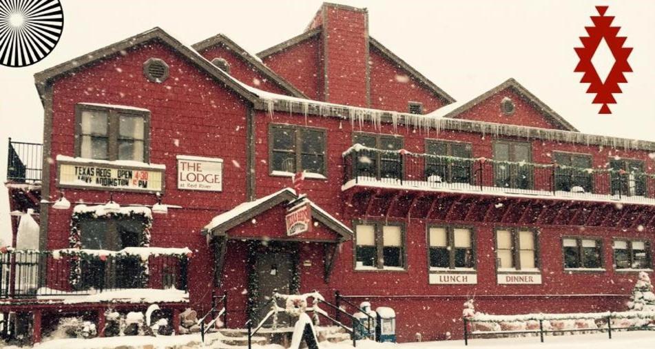un gran edificio rojo con nieve. en The Lodge at Red River, en Red River