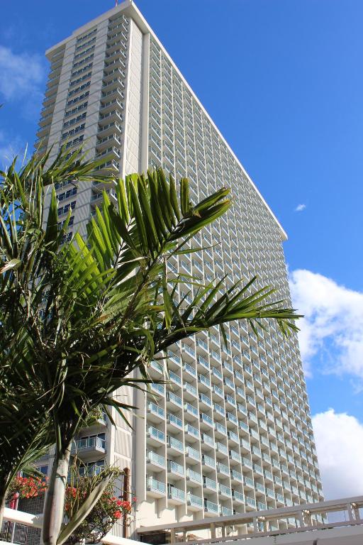 a tall building with a palm tree in front of it at LSI Resorts at Ala Moana in Honolulu