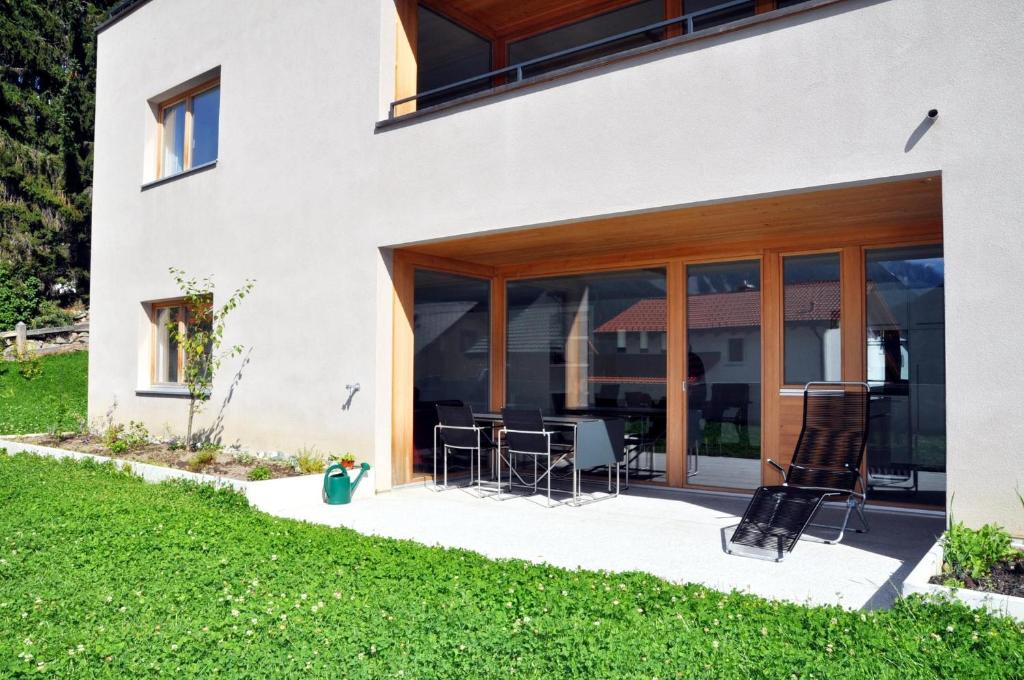 ein Haus mit Glastüren und Stühlen auf einer Terrasse in der Unterkunft Crastuoglia 720 - Nr. 1 in Scuol