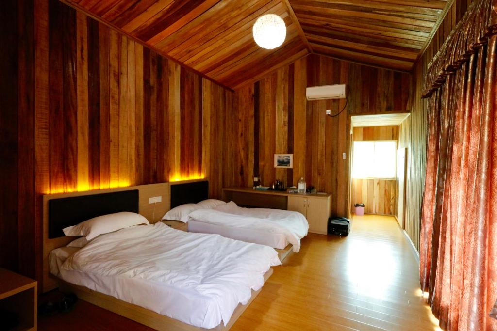 two beds in a room with wooden walls at Shunde Palm Resort 仙本那顺德人家棕榈园 in Semporna