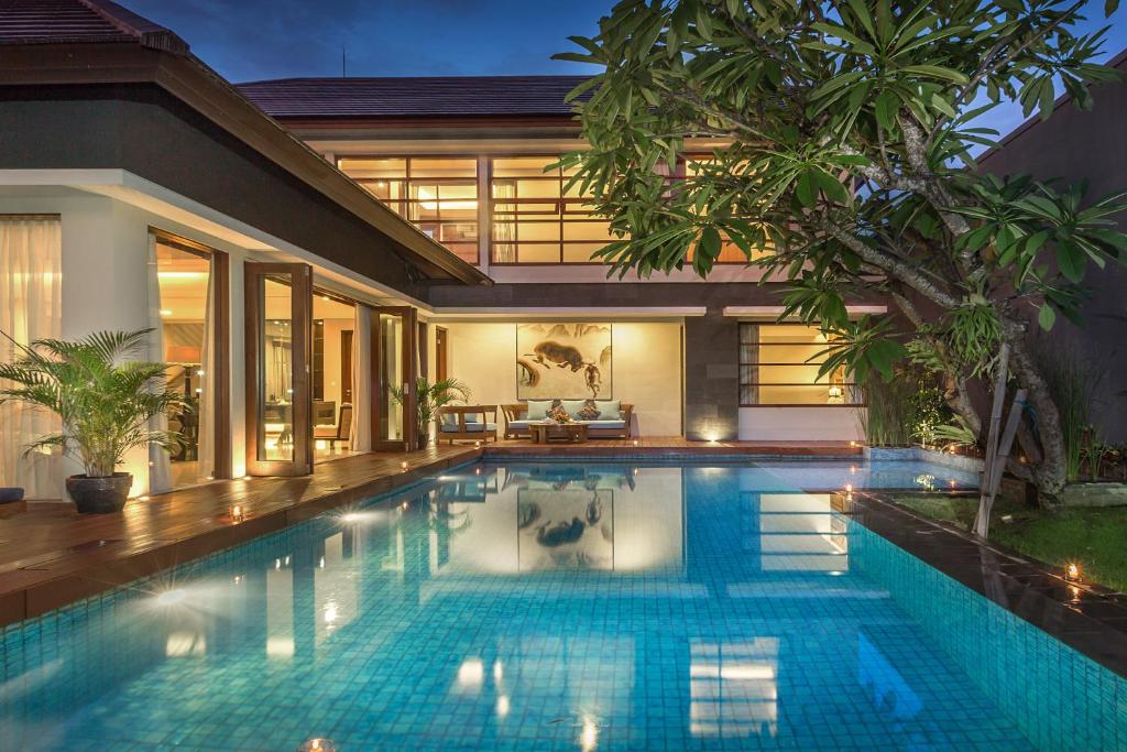 a swimming pool in front of a house at Entrada Seminyak Villa By Nagisa Bali in Seminyak