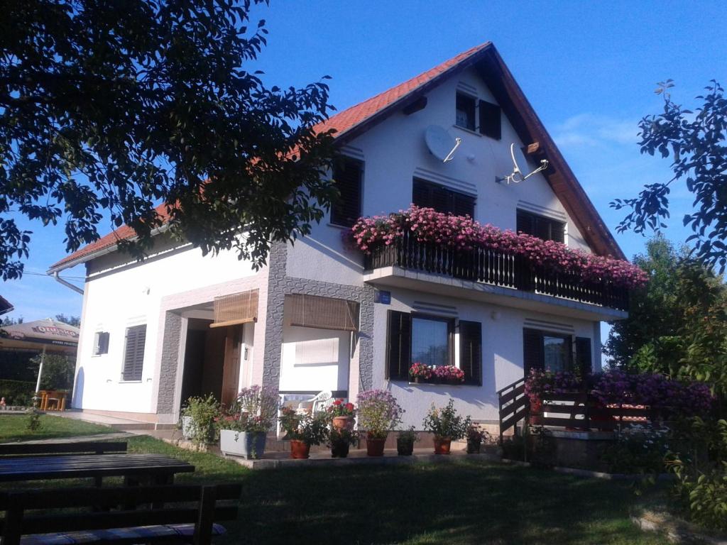 a white house with flowers on the balcony at Guest House Adrijana in Seliste Dreznicko