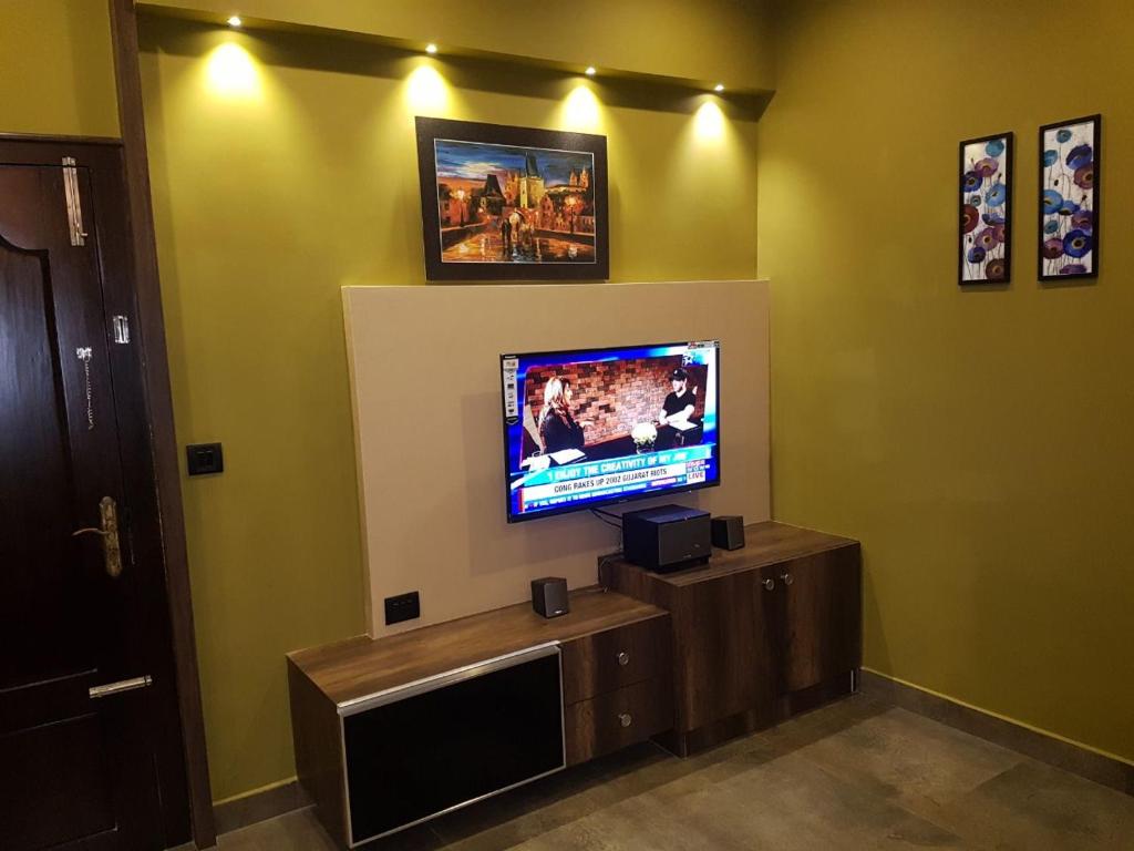 a living room with a flat screen tv on a wall at Belen - Service Apartment in Mangalore