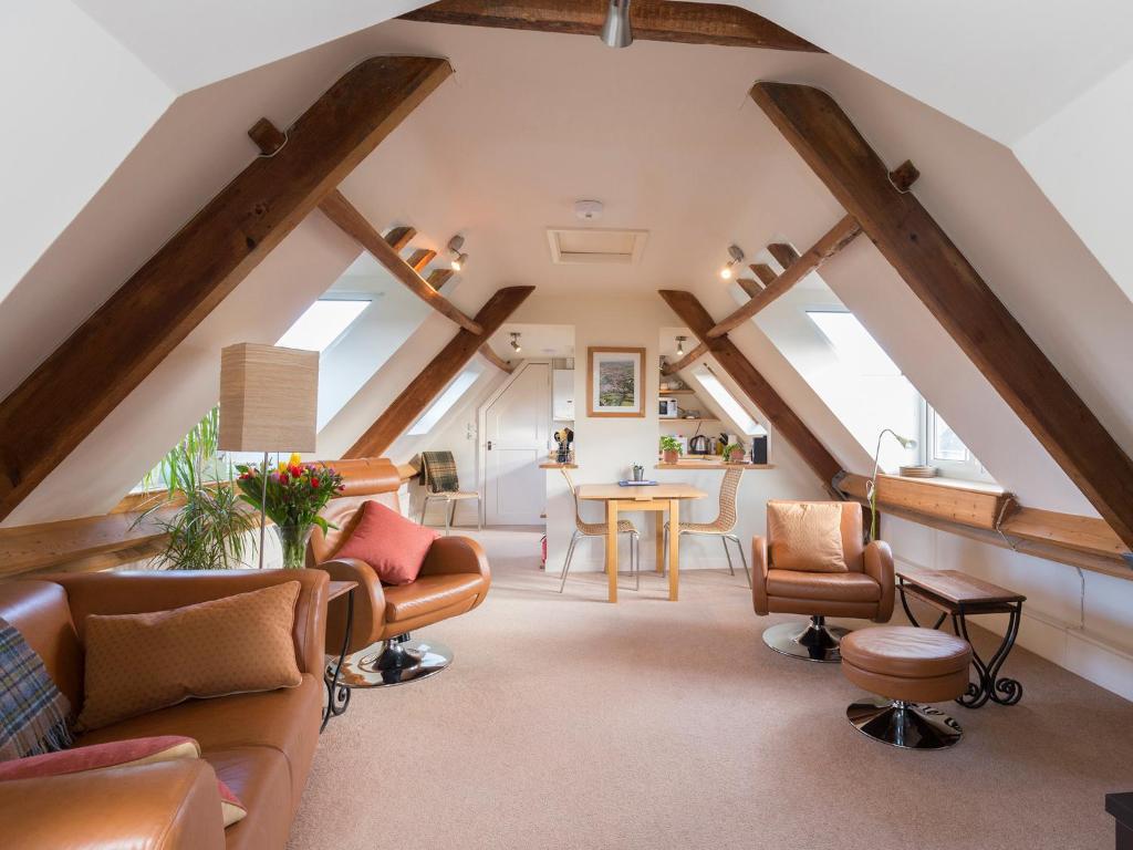 an attic living room with wooden beams and furniture at The Leat at Wynyard Mill in Malmesbury