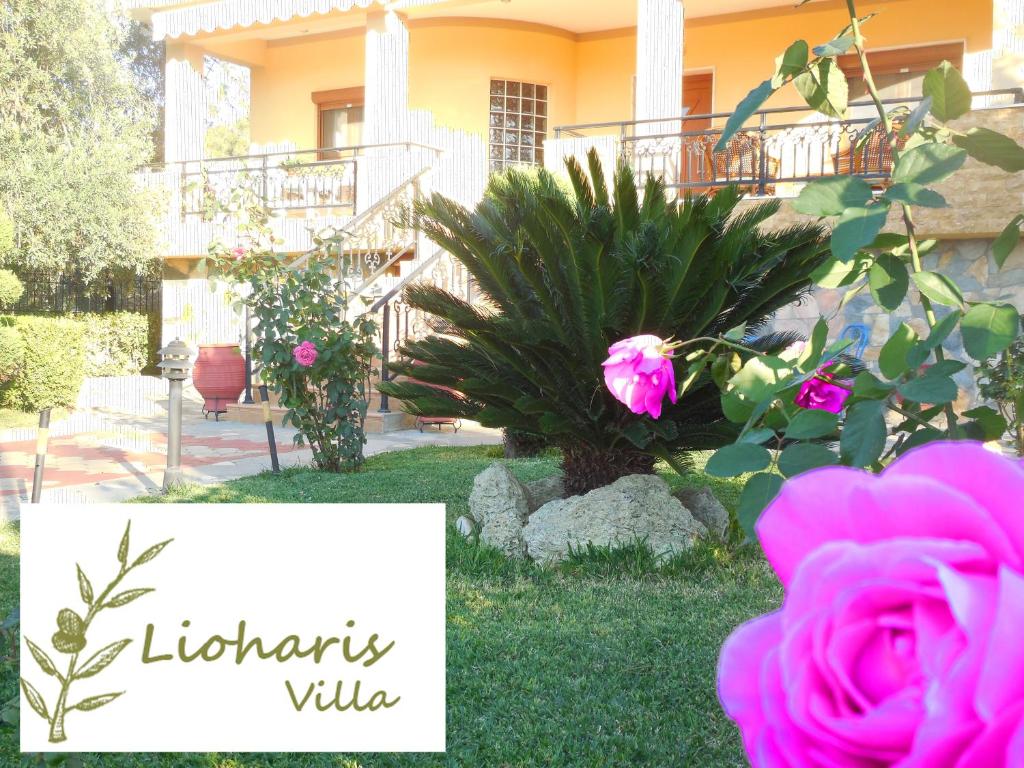 a sign in front of a house with pink roses at Lioharis Villa in Skala Rachoniou