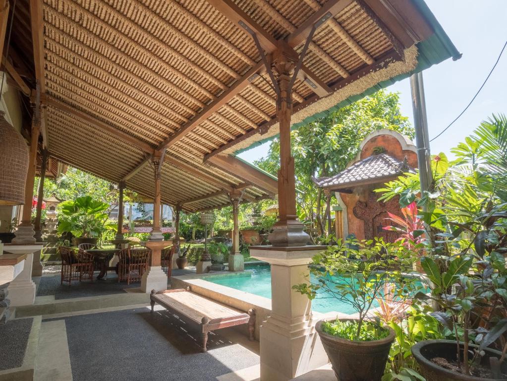 a pavilion with a pool and a table and some plants at Maruti Lane Villa in Ubud