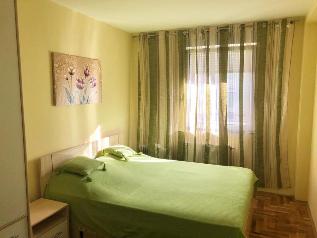 um quarto com uma cama verde e uma janela em Apartman Ivana em Novi Sad