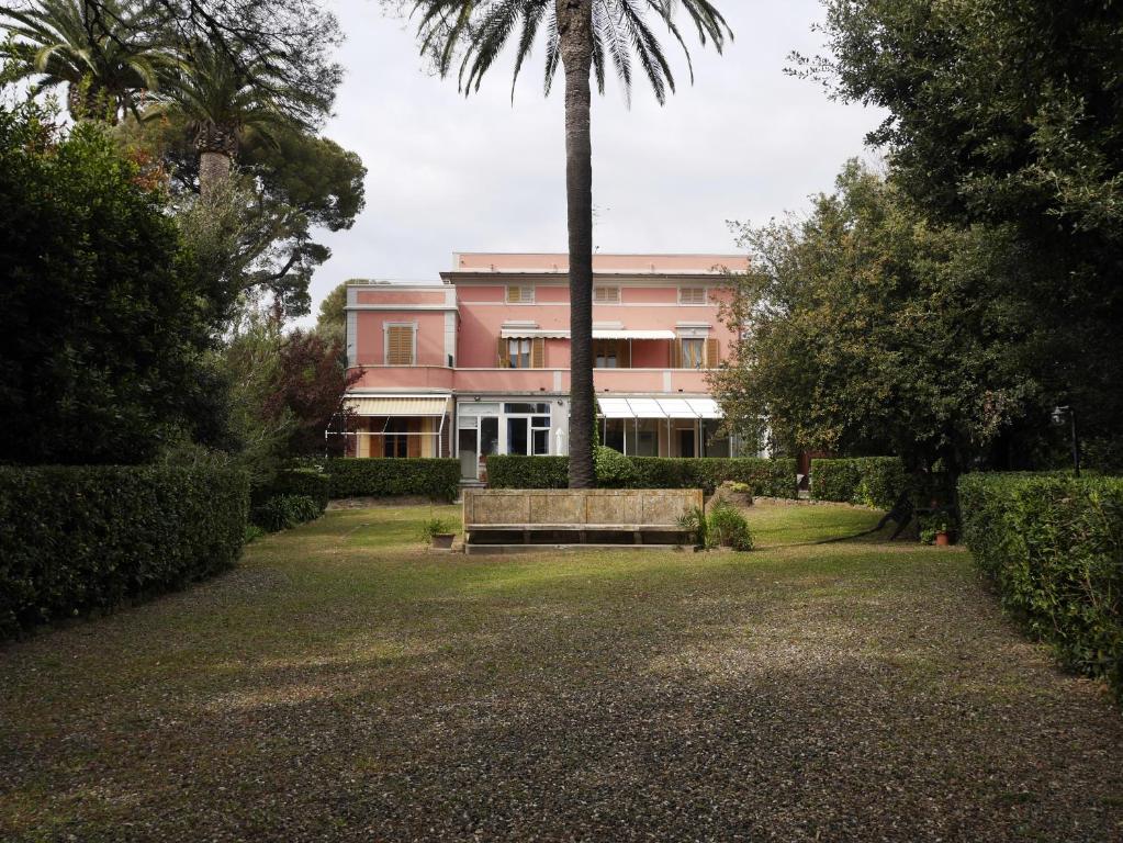 ein rosafarbenes Gebäude mit einer Bank und einer Palme in der Unterkunft Monolocale in villa in Castiglioncello