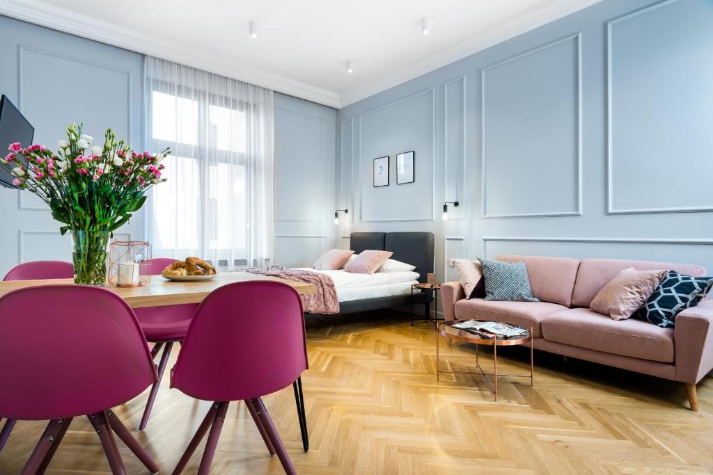 un soggiorno con divano e tavolo con sedie viola di P&J Luxury Apartments a Cracovia
