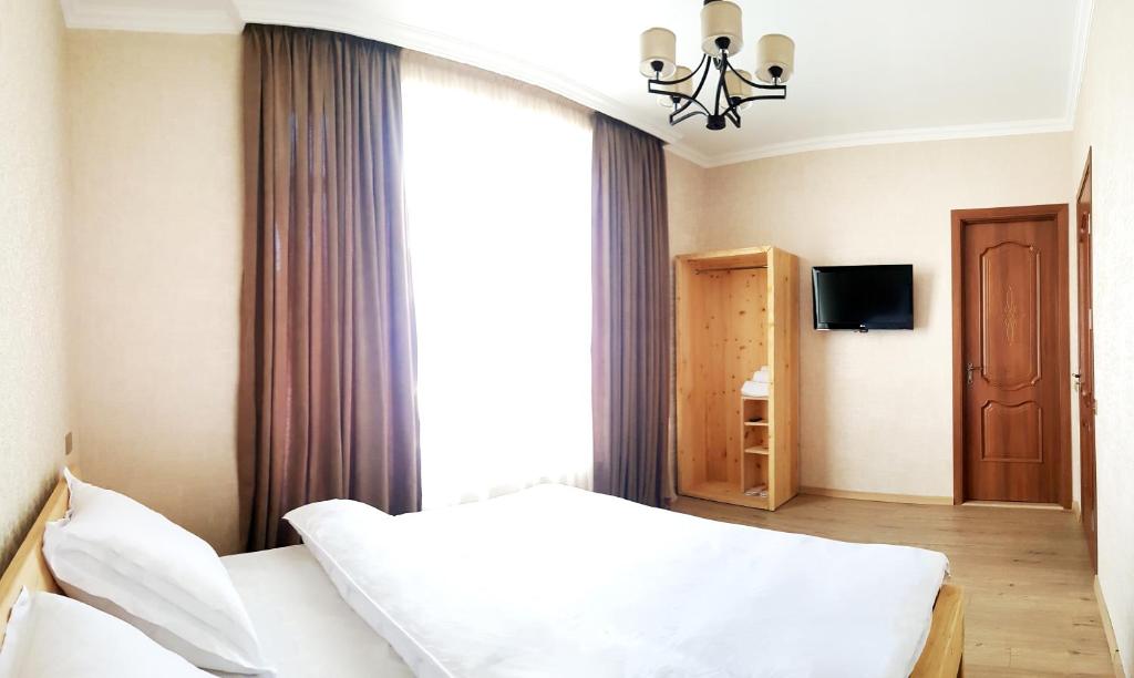 um quarto com uma cama branca e uma janela em Cozy Hotel Kazbegi em Stepantsminda