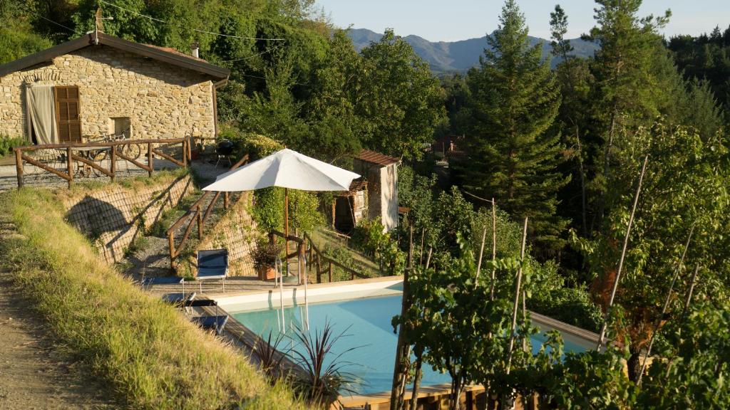 - une piscine avec un parasol à côté d'une maison dans l'établissement Casa del'Orto, à Bigliolo