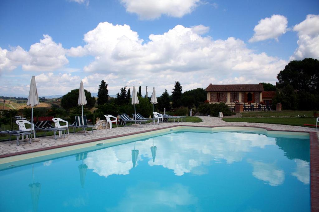 una grande piscina con sedie e ombrelloni di Agriturismo Le Docce a Castelfiorentino