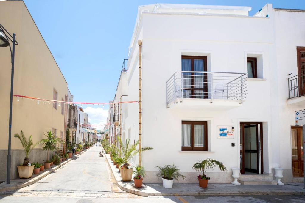 a street with white buildings and potted plants at Il Mare Dentro Rooms in San Vito lo Capo