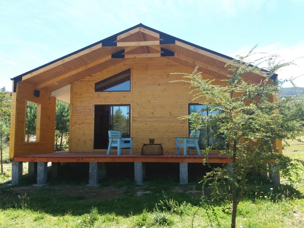 una casa de madera con 2 sillas en una terraza en Cabañas Rincon del Sur, en Cochrane