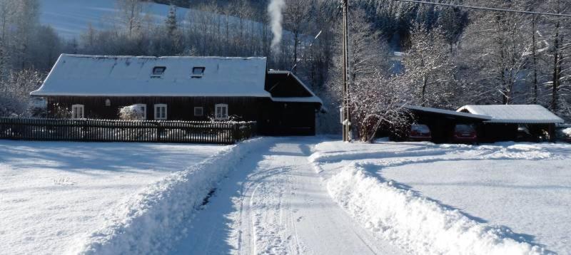 a snow covered road leading to a house with a building at Apartman Sverana in Velké Karlovice