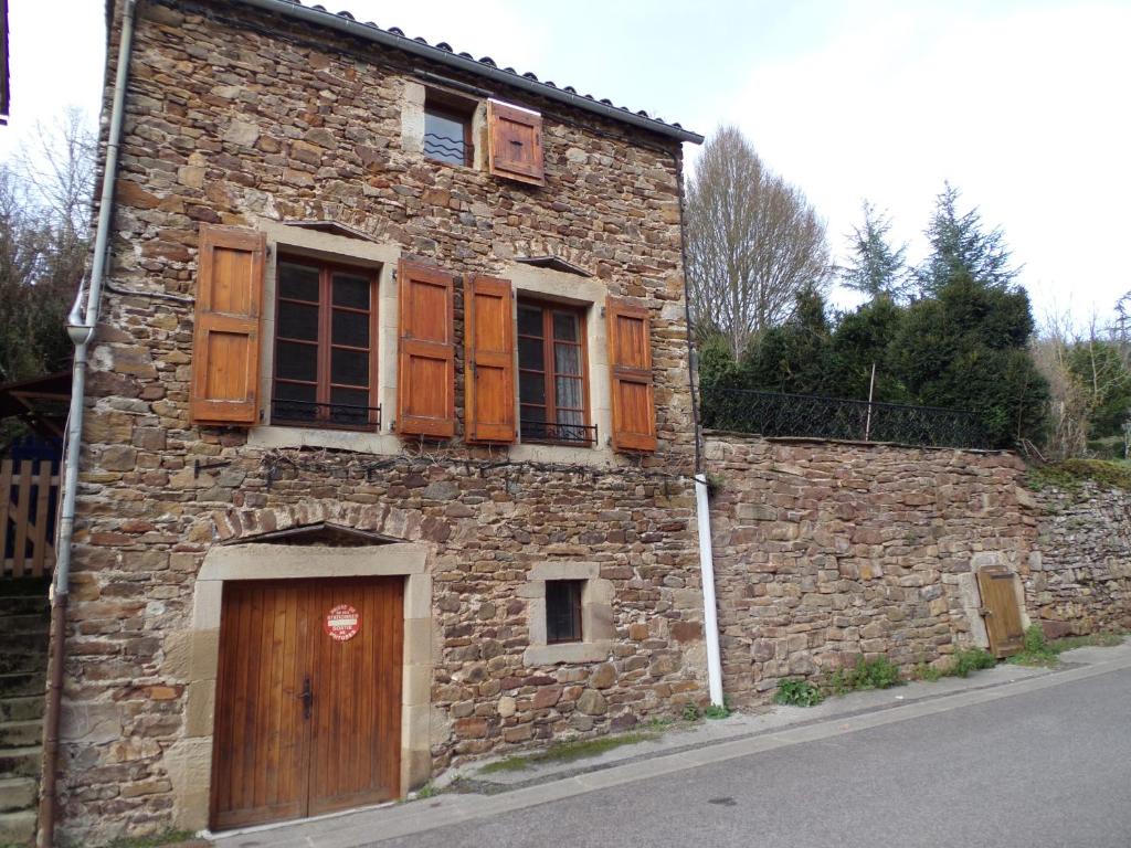 an old stone building with wooden windows and a door at maison avec jardin in Sylvanès