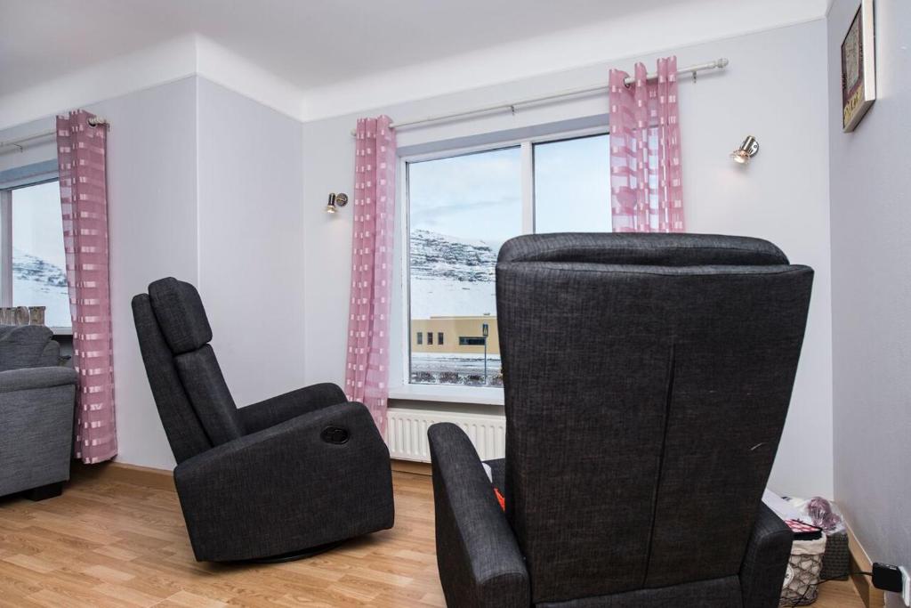 einen schwarzen Stuhl im Wohnzimmer mit Fenster in der Unterkunft Guesthouse 43 in Grundarfjörður