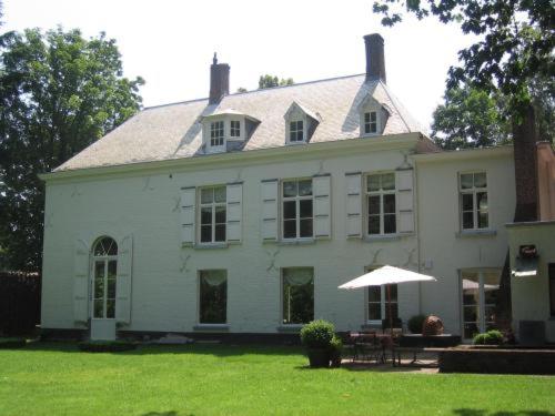 una gran casa blanca con un paraguas en el patio en B&B 't Wit Huys Brugge, en Brujas