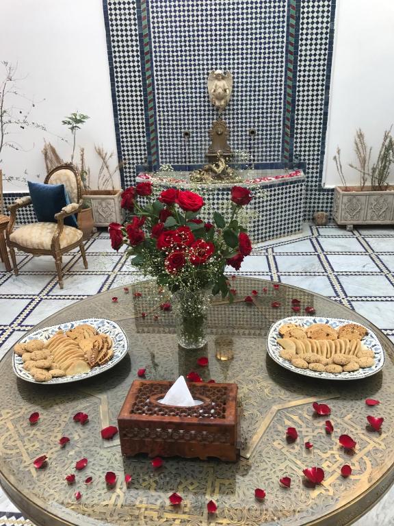 a table with red roses and plates of food on it at Riad Amor - Suite & Spa in Fès