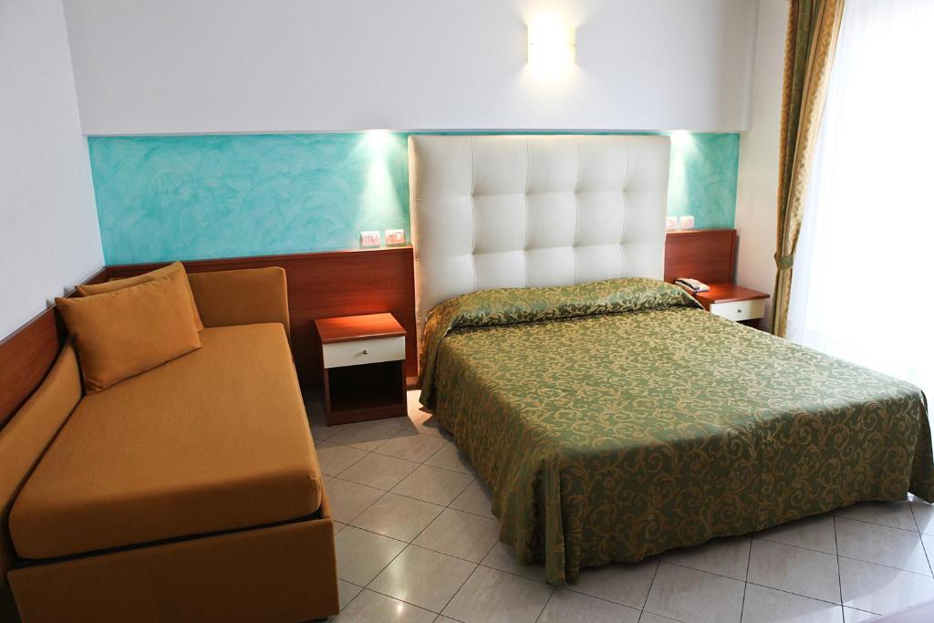 リッチョーネにあるHotel Gabbianoのベッドとソファ付きのホテルルーム