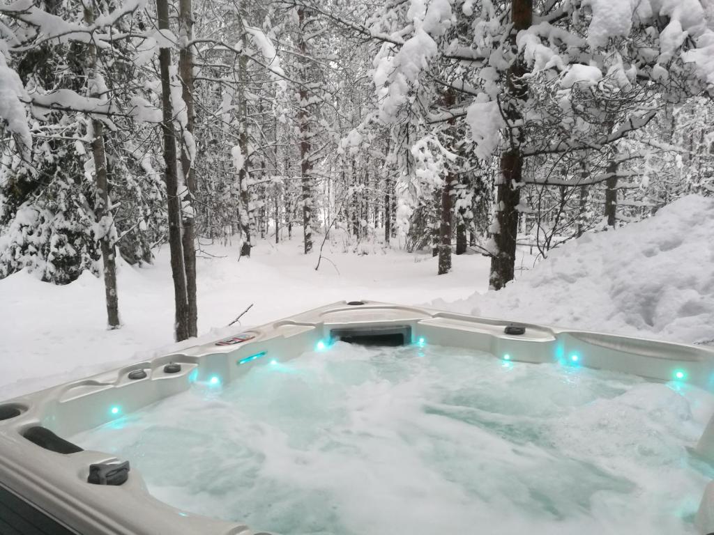 eine Whirlpool-Badewanne in einem schneebedeckten Wald in der Unterkunft Syöte Cottage in Syöte