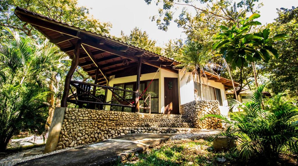 a house with a stone wall and a porch at Cabinas Las Olas in Playa Avellana