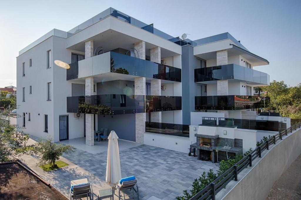 een appartementencomplex met een patio en een paraplu bij Deluxe new apartments - few steps from the beach - luxury holiday with style - by TRAVELER tourist agency Krk in Krk