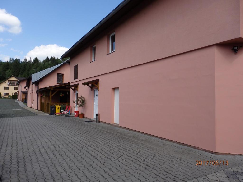 ein rosafarbenes Gebäude mit einer Backsteinstraße daneben in der Unterkunft Ubytovanie Erika in Vitanová