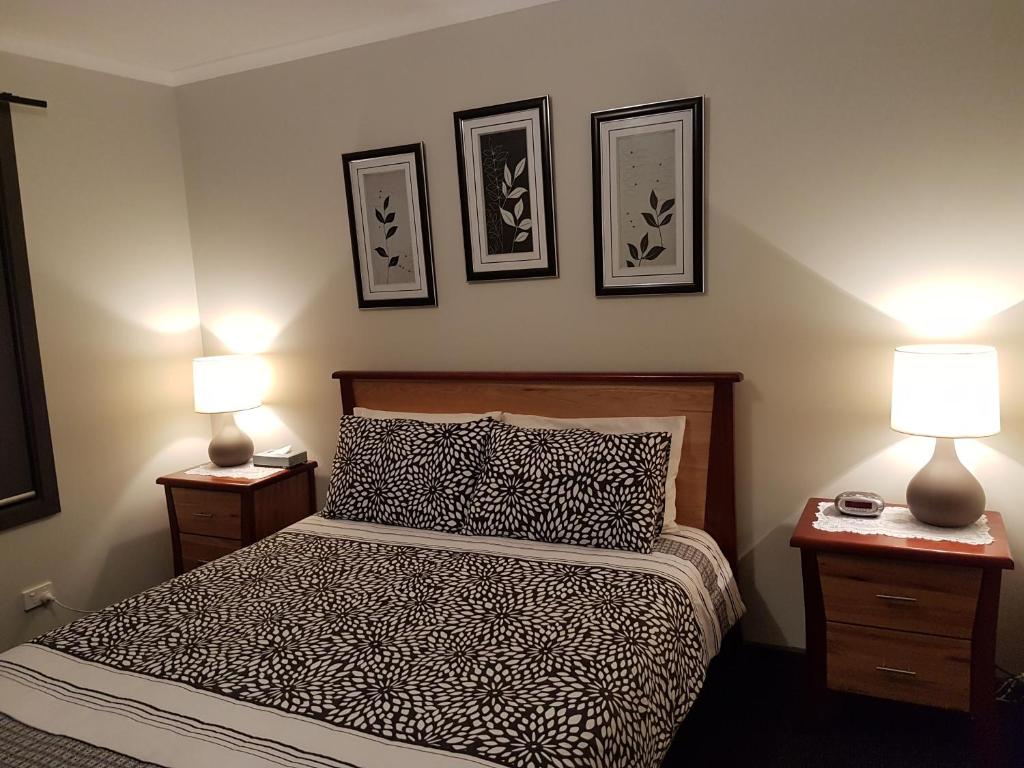 ein Schlafzimmer mit einem Bett mit zwei Lampen und Bildern an der Wand in der Unterkunft Wudinna Farm View in Wudinna