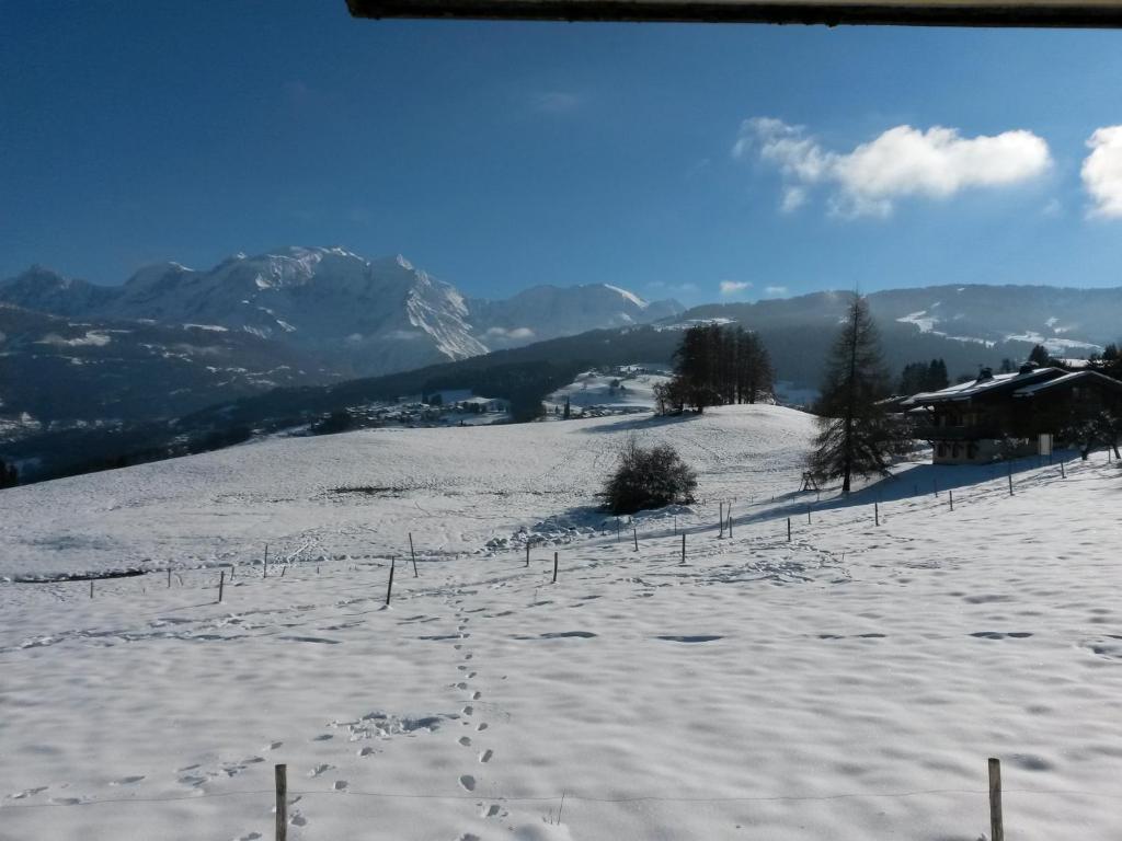 Rez de chaussée très calme vue Mont-Blanc في كومبلو: تل مغطى بالثلج مع سياج وجبال