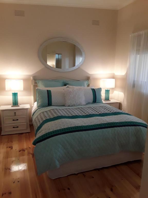 a bedroom with a bed with two lamps and a mirror at Bay Bell Cottage in Saint Leonards