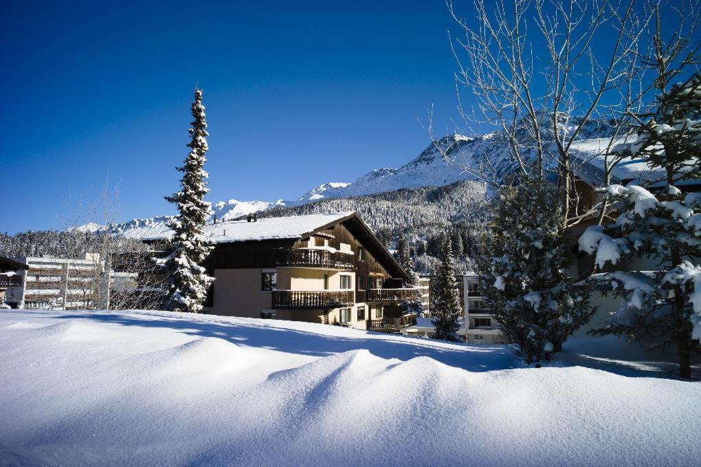 un cortile coperto da neve con una casa sullo sfondo di Seestrasse 1 (292Ap) a Lenzerheide