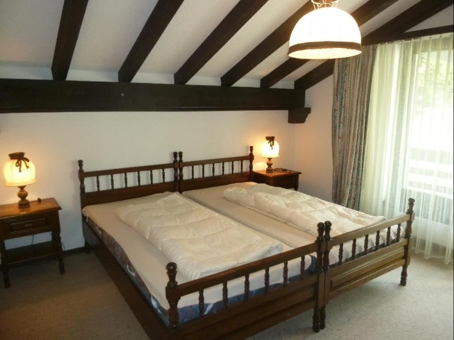 um quarto com uma cama de madeira com 2 mesas e uma janela em La Schmetta 5 (334 Fo) em Lenzerheide