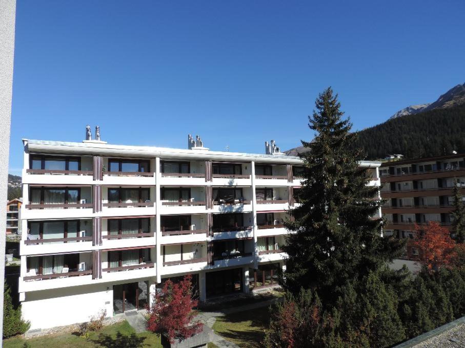 un immeuble d'appartements blanc avec un arbre en face dans l'établissement Astoria (104 Mu), à Lenzerheide