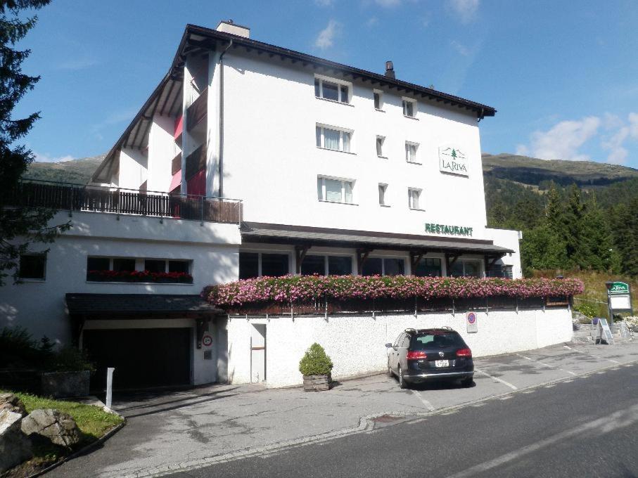 a white building with a car parked in front of it at La Riva (159 Br) in Lenzerheide